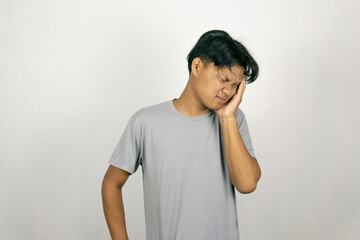 Indonesian man holding his head with his hands, showing a depressed facial expression, and experiencing a headache. isolated on a white background