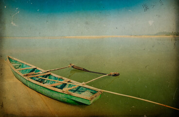 Scenic view of run-down green fisherman boat with wooden paddles lying on empty sandy seashore...