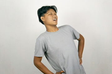 Young Asian man experiencing work related muscle pain and stiffness. Concept of healthcare and medicine. Isolated on white background.