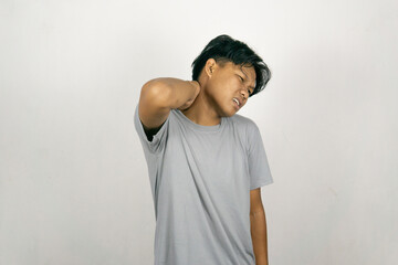 Young Asian man experiencing work related muscle pain and stiffness. Concept of healthcare and medicine. Isolated on white background.