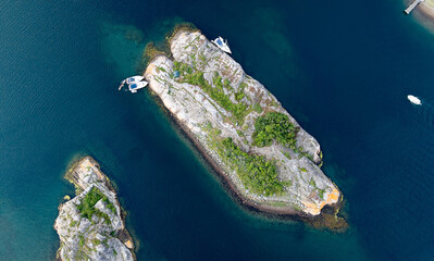 Top-Down Aerial View of Small Rocky Island Near Str&ouml;mstad, Sweden with Green Vegetation and Boats Moored Along the Shore in Clear Blue Water
