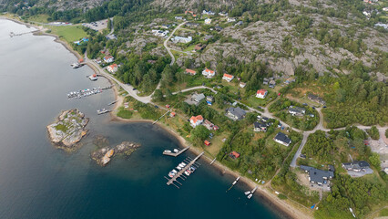 Top-Down Aerial View of Seaside Residential Area Near Str&ouml;mstad, Sweden with Docks, Houses, Rocky Terrain, and Forested Hills by a Calm Coastline