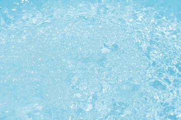 Blue water with ripples on the surface. Defocus blurred transparent blue colored clear calm water surface texture with splashes and bubbles. Water waves with shining pattern texture background.