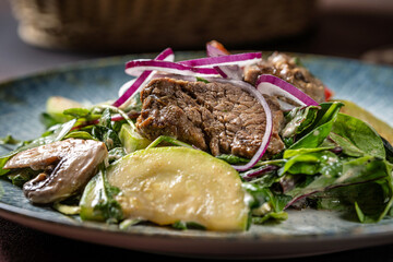 Closeup of warm beef salad with avocado and red onion