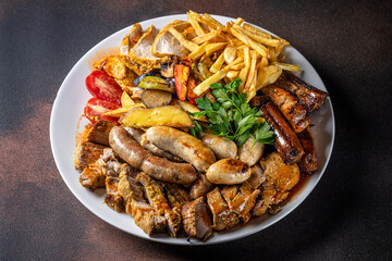 Assorted grilled meats and sausages with fries and vegetables
