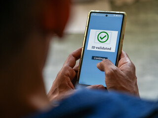 Man got successful ID validation message on his mobile phone confirming his identity document is authentic. Selective focus on the display.