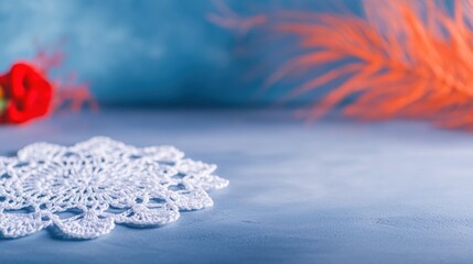 Close up of a beautifully handcrafted white crochet doily placed on a smooth surface. Vivid orange and red elements in the background create an artistic contrast and enhance the scene