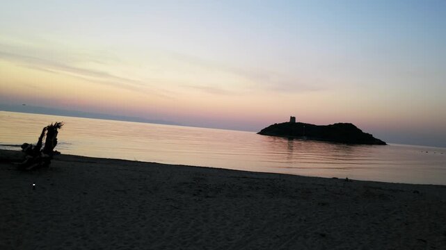 San Macario Islet seen from pula beach at sunset, Italy, Sardinia. Slow tilting aerial