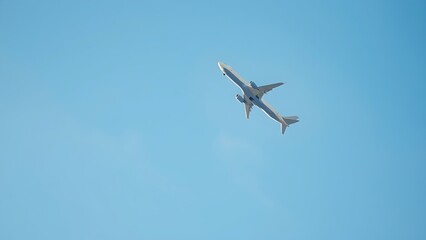 Airplane ascending into a clear blue sky with soft clouds.
