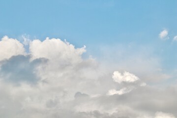 A mix of dark grey storm clouds and bright white cumulus formations against a pale blue sky, showing the transition of weather and dramatic atmospheric contrast.