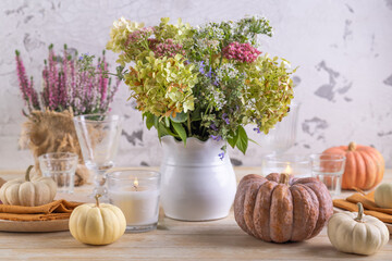 Beautiful bouquet of autumn flowers in pumpkin on festive dining table