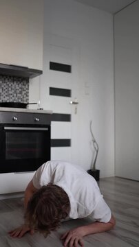 Vertical screen young man suddenly feeling unwell collapsing on kitchen floor concept of sudden illness weakness dizziness emergency situation at home everyday health problem scene