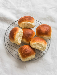 Homemade buns on a baking rack on a light background, top view