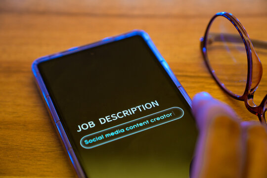 Man filling out the job description page on his mobile phone as social media content creator. Selective focus on the display.