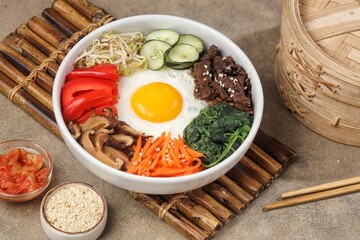 Bibimbap is a Korean dish in the form of a bowl of white rice topped with side dishes of vegetables, beef, eggs and spicy gochujang sauce.
