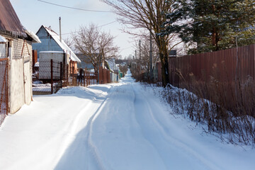 A snow covered road with a fence on the side