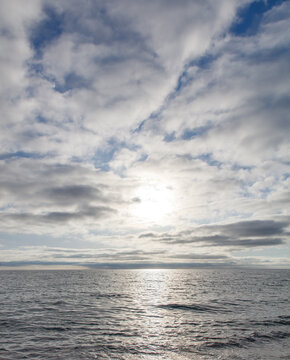Fototapeta A calm ocean with a bright sun shining on the water