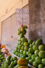 tropical display of ripe mangoes hanging from ropes and neatly arranged on a wooden table at a traditional market in Cirebon. everyday rhythm celebrate Indonesia’s tropical abundance