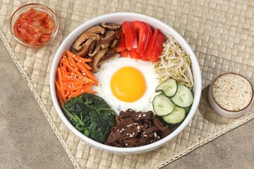 Bibimbap is a Korean dish in the form of a bowl of white rice topped with side dishes of vegetables, beef, eggs and spicy gochujang sauce.