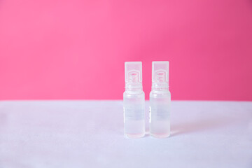 Two clear spray bottles on a white surface against a pink background. The bottles are identical in shape and size, designed for dispensing liquid.