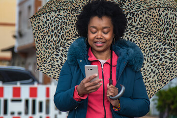woman with umbrella looking at mobile phone on the street