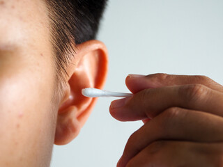 Young man ear cleaning with cotton swab showing close up skin texture and careful hygienic routine