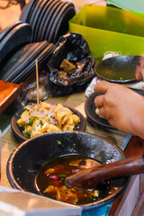 mouth-watering view of tahu gejrot being prepared at a street stall in Cirebon. Fried tofu pieces soak in sweet-spicy sauce with shallot, garlic, and chili rich flavors and social food culture of Java