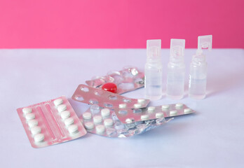 Assorted medication packaging including tablets and spray bottles on a pink background. Focus on health and wellness products.