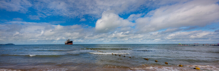 panoramic view of the sea and clear autumn sky where an old cargo ship is anchored	
