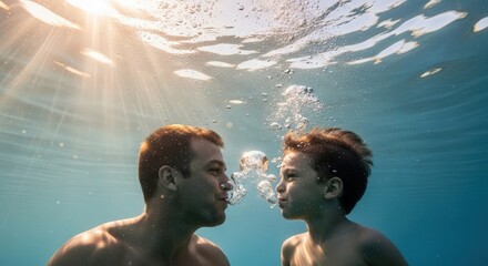Father and son playing together underwater, blowing bubbles on a sunny day in clear blue water