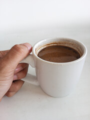 Hot black coffee in a white mug on a white table