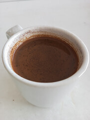 Hot black coffee in a white mug on a white table