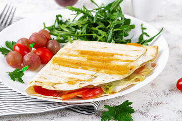 A healthy breakfast. Lavash with cheese, tomatoes, and herbs. Fresh salad.