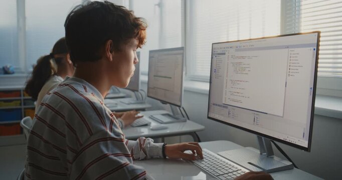 University Students Sit at Computers in Well Lit Classroom Opposite Window, Writing Program Code. Concept of Group Learning, Collaboration, Software Development, and Digital Education. Dolly Shot.