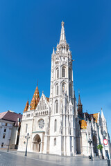 Fototapeta premium Majestic view of Matthias Church in Budapest, Hungary, under a clear blue sky. Stunning architecture and colorful tiled roof