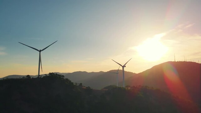 Wind generators on a ridge line during sunrise, aerial drone view. Energy transition with renewable wind contributing to net-zero