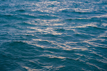 Water ripple surface texture, Rippling water surface with sunset reflection ripples. Golden sunset on rippling ocean waves. Tranquil water ripples reflecting sunlight.