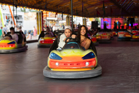 Friends enjoying bumper car ride at fair with laughter and vibrant lights