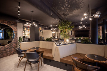 Elegant dining interior with modern lights, greenery, and glowing bar counter