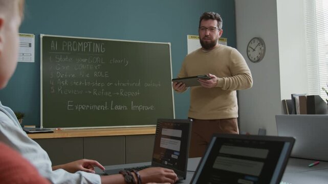 Medium shot of enthusiastic nerdy young male Caucasian teacher in eyeglasses explaining AI prompting rules to multiethnic students, pointing at blackboard, while conducting computer education lesson