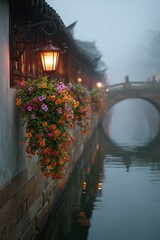 On a foggy day, streetlights hang on the walls of buildings in the water town, and orange flowers are next to them.