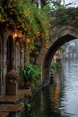 On a foggy day, streetlights hang on the walls of buildings in the water town, and orange flowers are next to them.