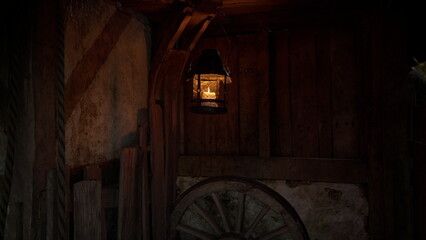 Fototapeta premium A soft glow from a hanging lantern fills a rustic sheds dark corners, showcasing wooden beams and a large wagon wheel, creating an inviting atmosphere at twilight.