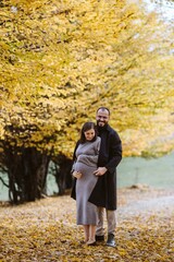 Pregnant couple expecting baby standing in autumn park