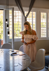 Woman arranging plates on dining table in bright room with sunlight