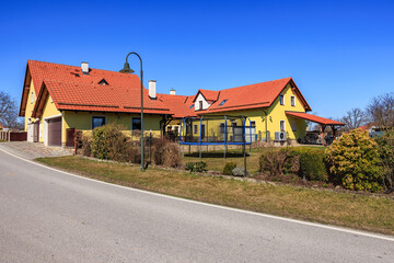 Sunny suburban house with red roofs and trampoline in bright neighborhood