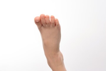 Obraz premium Close-up of a child's foot, toes slightly curled. Soft skin and delicate features are visible against a white background.