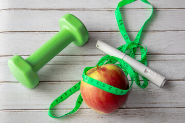 Healthy lifestyle concept with dumbbell, measuring tape, apple and Wegovy injection pen. Weight loss support and fitness background.