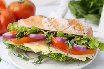 Delicious ciabatta sandwich with prosciutto, cheese and vegetables on white table, closeup