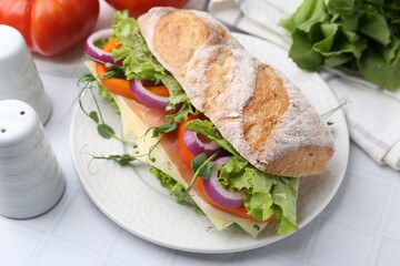 Delicious ciabatta sandwich with prosciutto, cheese and vegetables on white tiled table, closeup